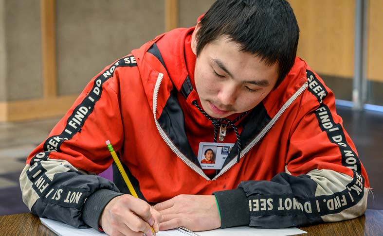 Young Alaskan student working through schoolwork in a classroom